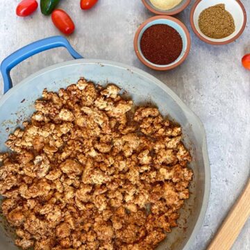 Quick and Easy Taco meat in a pan with seasonings, tomatoes and jalapeno surrounding it