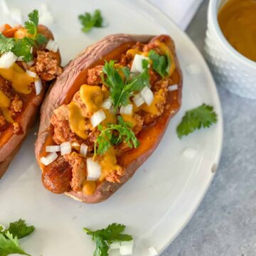 Paleo chili cheese dog in a sweet potato with onions and cilantro