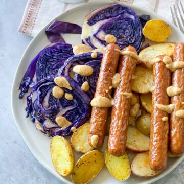 Sausages over roasted purple cabbage and potatoes with honey mustard sauce drizzled over