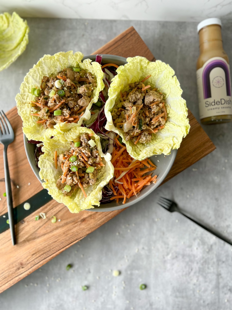 Pork Lettuce Wraps on a plate with cabbage and shredded carrots