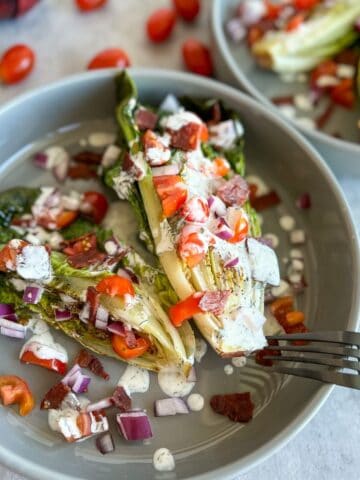 grilled wedge salad on a plate with tomatoes, onions, and ranch dressing