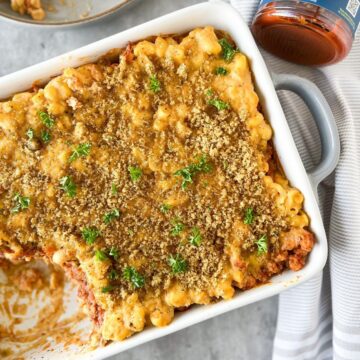 Sloppy joe mac and cheese in a white casserole dish with a scoop taken out