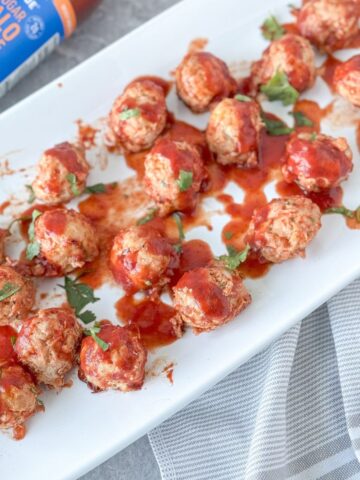 gluten-free chicken meatballs on a white plate with buffalo bbq sauce
