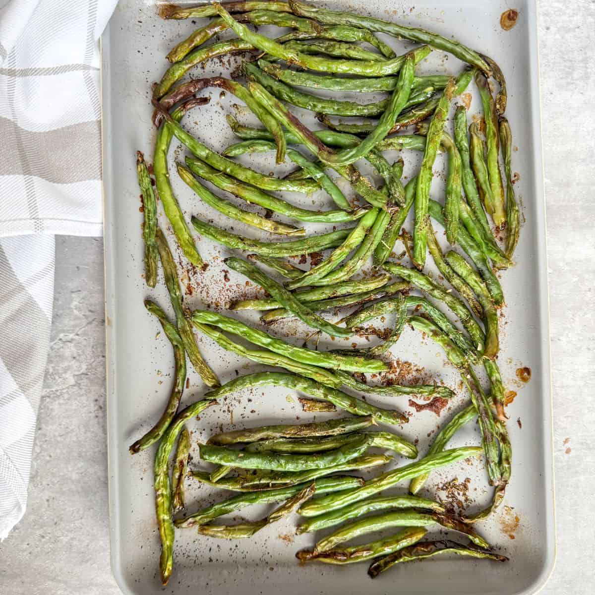 Oven roasted green beans on a pan, cooked.