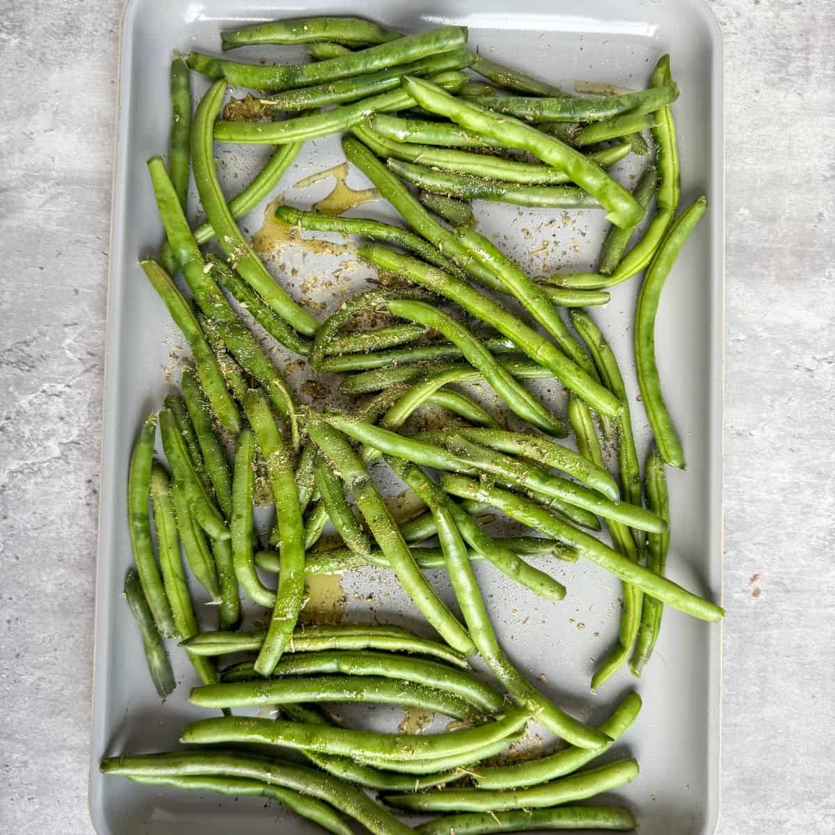 Oven roasted green beans on a pan step 1- season and oil the beans.